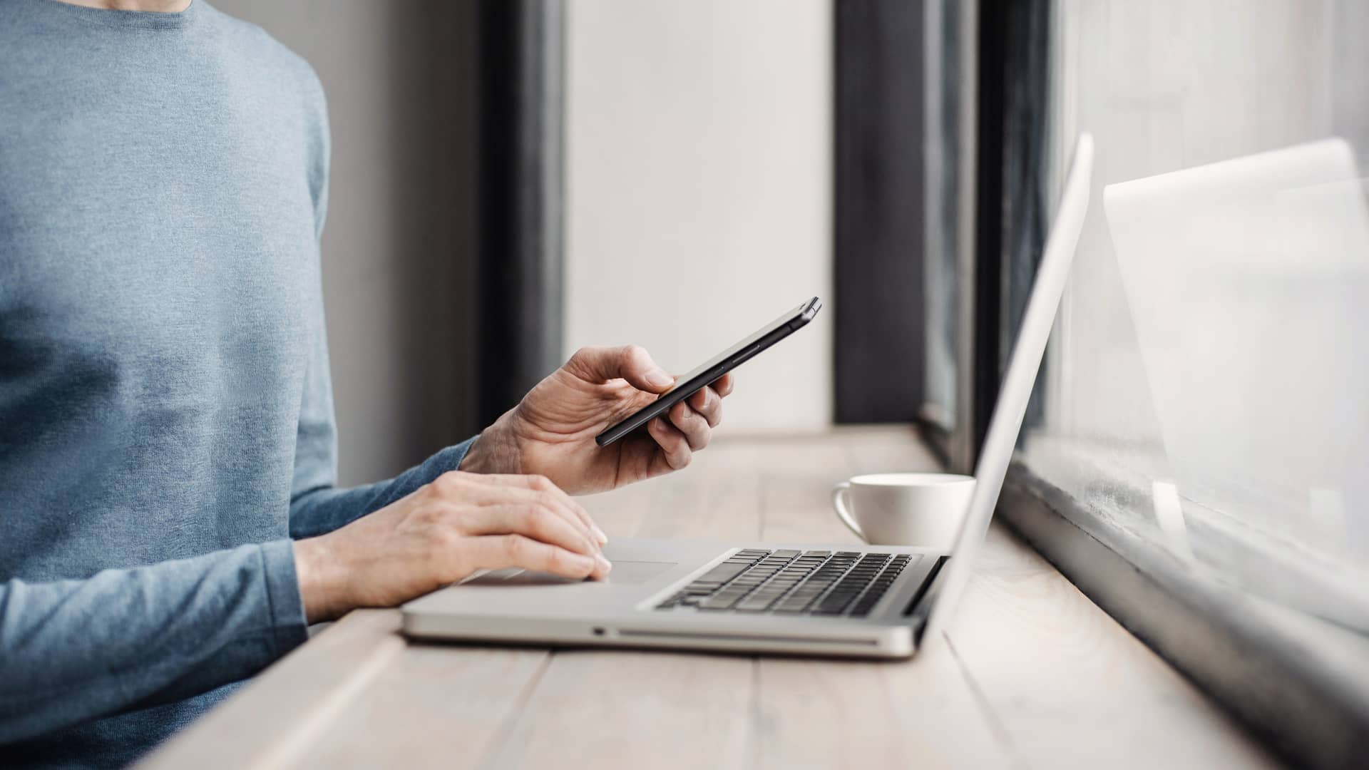 manos de alguien utilizando un celular y un portatil porque tiene contratado internet simetrico manos de alguien utilizando un celular y un portatil porque tiene contratado internet simetrico